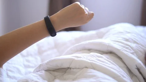 Beautiful woman checking data on her fitness tracker band after waking up in the Stock Footage 91657609
