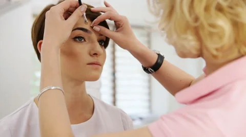 Beautiful woman drawing a shape of eyebrows using eyebrow pencil. Make up artist Stock Footage 64516479