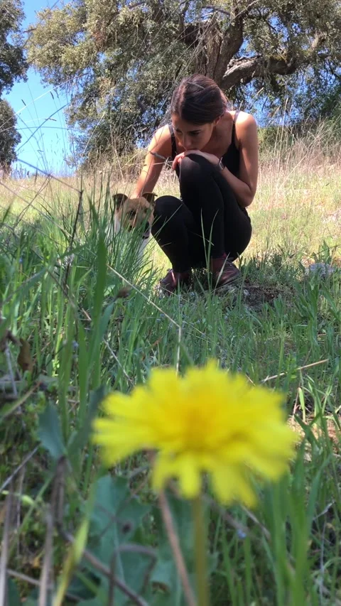 Beautiful woman enjoying springtime caressing her pet in nature Stock Footage