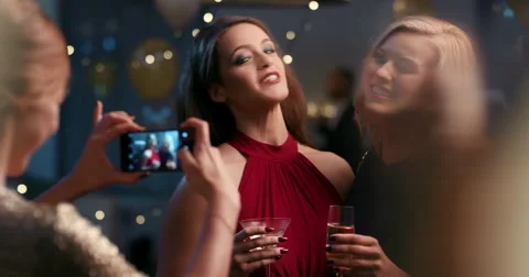 Beautiful woman at glamorous party taking photo with smart phone for social Stock Footage