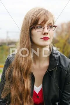 Beautiful woman in glasses in leather jacket looks away outdoor Stock Photos