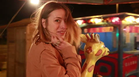 Beautiful woman having fun riding carousel in amusement park Stock Footage