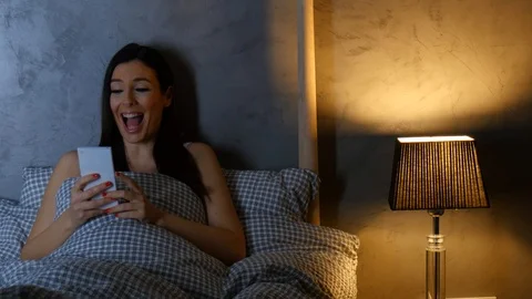 A beautiful woman having fun using her smartphone at night in bed Stock Footage 101837567