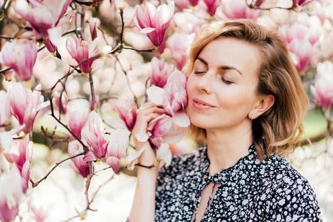 Beautiful woman in her forties. Profile portrait with a pink flowering magnol Stock Photos