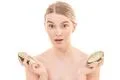 The beautiful woman holding two halves of a avocado on the white background Photo