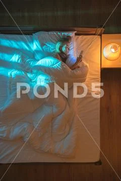 The beautiful woman lay on the bed and phone. Evening night time. View from.. Stock Photos