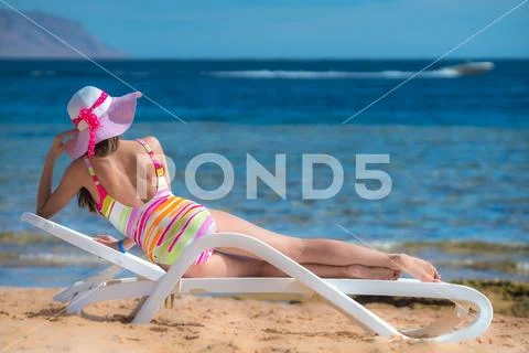 The beautiful woman lay on the sunbed on the sea background Stock Photos