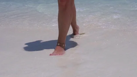 Beautiful woman legs walking on the beach Stock Footage