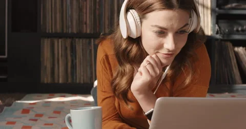 Beautiful woman listening to music on laptop at home headphones drinking coffee Stock Footage