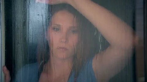 Beautiful woman looking out window in rain Stock Footage