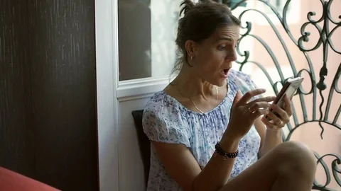 Beautiful woman looks surprised while browsing internet on smartphone, steadycam Stock Footage