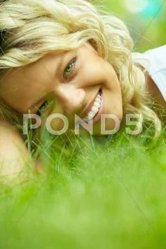 Beautiful woman lying on grass and smiling at camera Stock Photos