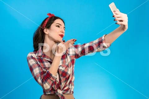 The beautiful woman makes a selfie on the blue background Stock Photos