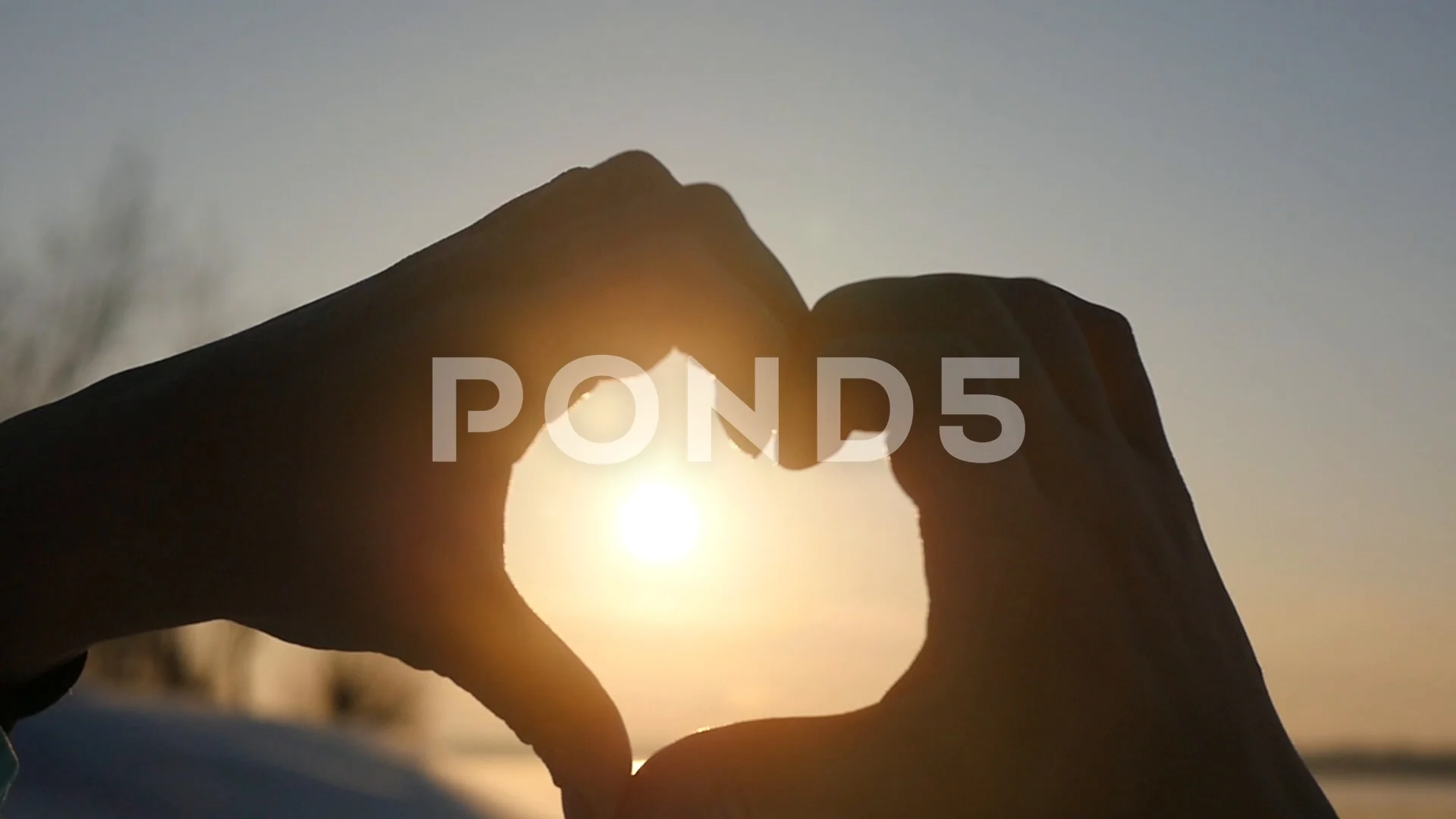 Beautiful Woman making heart shape with hands at sunset Girl holding up love