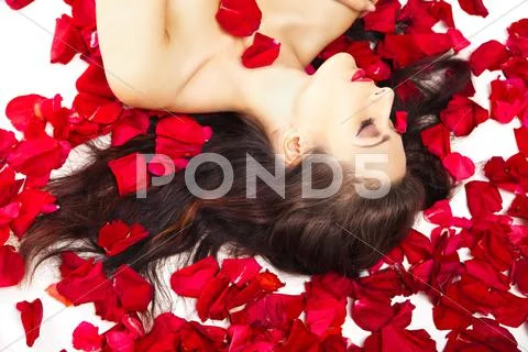 Beautiful woman in petals of red roses over white Stock Photos