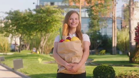 Beautiful woman posing in front of the camera she holding eco bag full of food Stock Footage 194416064