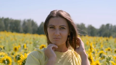 Beautiful woman posing while standing in a field with sunflowers Stock Footage 113785889