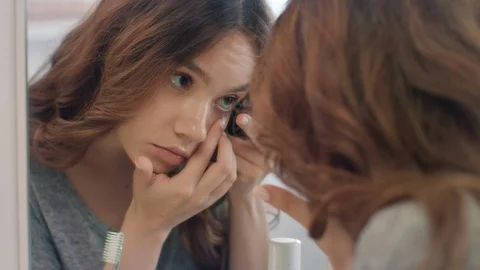 Beautiful woman putting on contact lenses at mirror in home bathroom Stock Footage