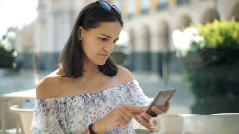 Beautiful woman relaxing in the cafe and browsing internet on smartphone, steady Stock Footage