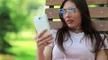 Beautiful woman sits on the bench and communicates via smartphone HD Footage