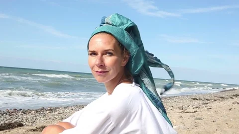 Beautiful woman sitting on the beach and smiling Stock Footage
