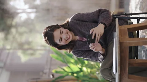 Beautiful woman sitting at a cafe using mobile phone and smiling. Female reading Stock Footage 262320096
