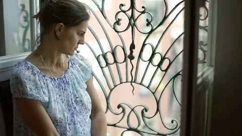 Beautiful woman sitting next to the window and looks very worried, steadycam sho Stock Footage
