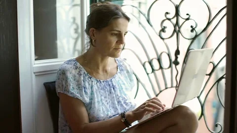 Beautiful woman sitting next to the window and using modern notebook, steadycam Stock Footage