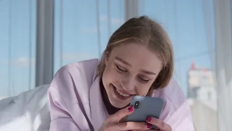 Beautiful woman smiling while using mobile phone on bed Stock Footage 164539892