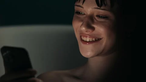 A Beautiful woman smiling while using her phone in the bathtub alone Stock Footage 274945816