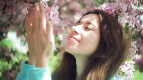 Beautiful woman sniffing flowers in the spring garden Stock Footage