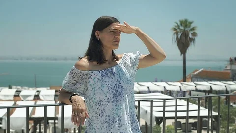 Beautiful woman standing on the balcony with view on the sea and looking around, Stock Footage