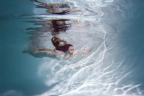 Beautiful woman swims underwater in the pool. Stock Photos