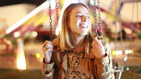 Beautiful woman on swing in amusement park, waving to camera Stock Footage 59556293