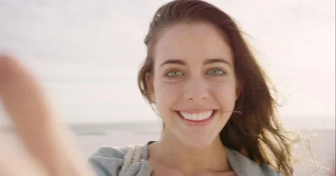Beautiful woman taking selfie using phone on beach at sunset smiling  Stock Footage