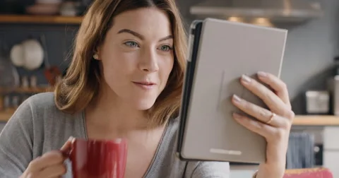 Beautiful woman talking to friends on internet using digital tablet app at home Stock Footage