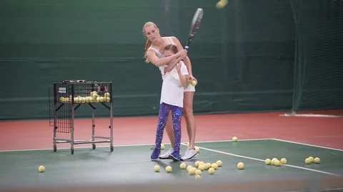 Beautiful woman tennis coach teaching little girl how to play tennis. Stock Footage