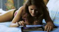 beautiful woman in underwear looking photos on the tablet lying on a bed HD Footage