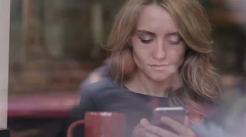 Beautiful woman using app on smartphone in cafe Stock Footage