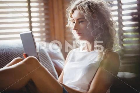 Beautiful Woman Using Digital Tablet In Living Room