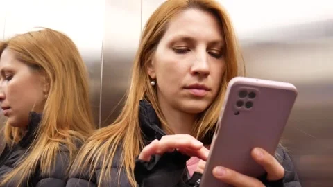 A beautiful woman using a smartphone while in elevator close-up Stock Footage 274781456