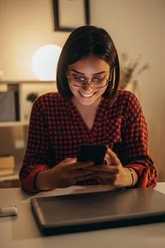 Beautiful woman using smartphone while working from home Stock Photos