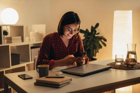 Beautiful woman using smartphone while working from home Stock Photos