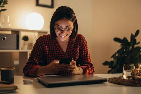 Beautiful woman using smartphone while working from home Stock Photos