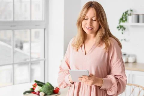 Beautiful woman using tablet computer in kitchen Foto stock