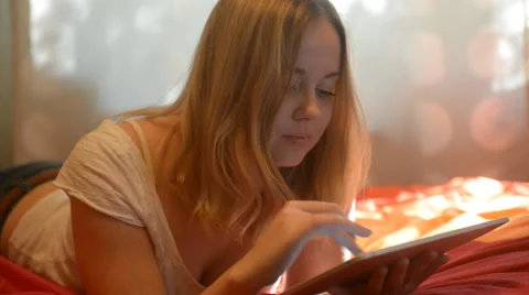 Beautiful woman using tablet lying on her bed Stock Footage 42006437
