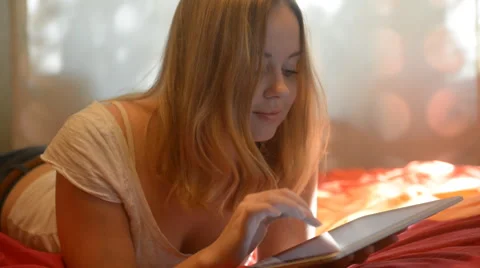 Beautiful woman using tablet lying on her bed Stock Footage 42006606