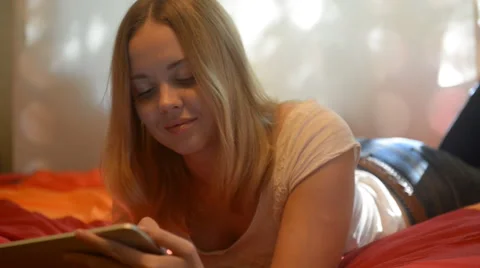 Beautiful woman using tablet lying on her bed Stock Footage 42007368