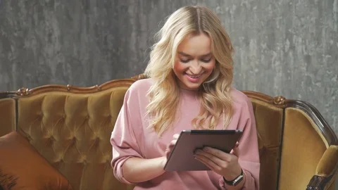 Beautiful woman using tablet sitting on sofa at studio. Stock Footage