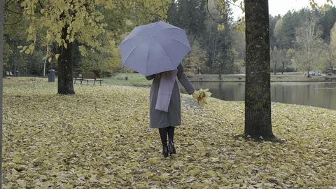 A Beautiful Woman with violet umbrella and scarf slowly walking Away into the Stock Footage